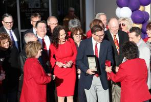 SJC receiving plaque after ribbon cutting and everyone smiling and celebrating