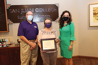 Lori Cheney holding a framed certificate and standing with Joe Rasor and Dr Pendergrass