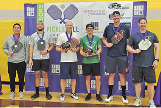 Team of men wearing medals holding Pickleball rackets and gear