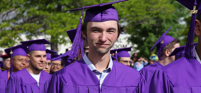 SJC Students at graduation.  Male smiling standing in line. 